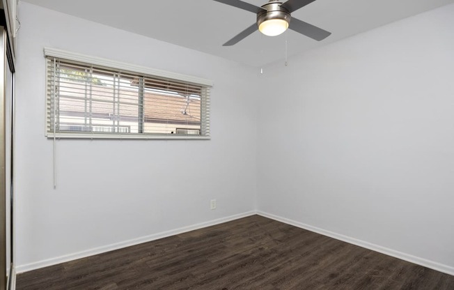 an empty room with a ceiling fan and a window