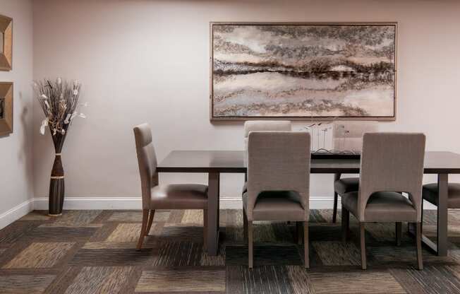 a dining room with a table and chairs and a painting on the wall