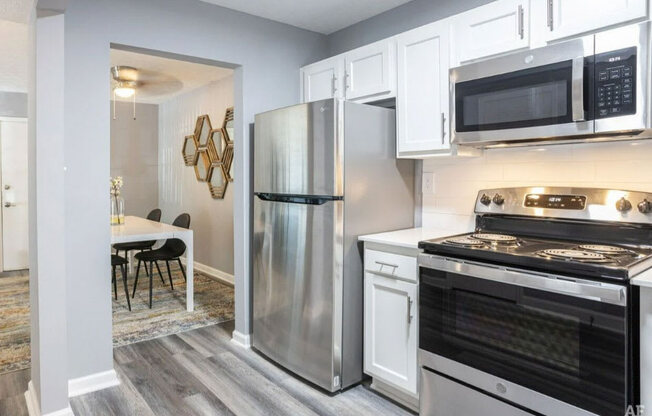 a kitchen with white cabinets and stainless steel appliances at Station JTown, Louisville Kentucky