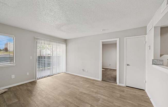 A spacious room with a sliding glass door and a wooden floor.