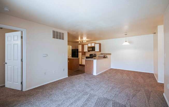 A living room with carpet and kitchen in the background