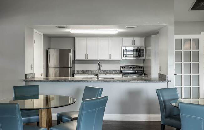 A modern kitchen with a glass table and blue chairs