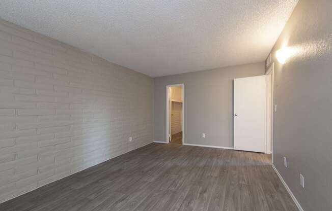 an empty living room with wood flooring and a door to a hallway