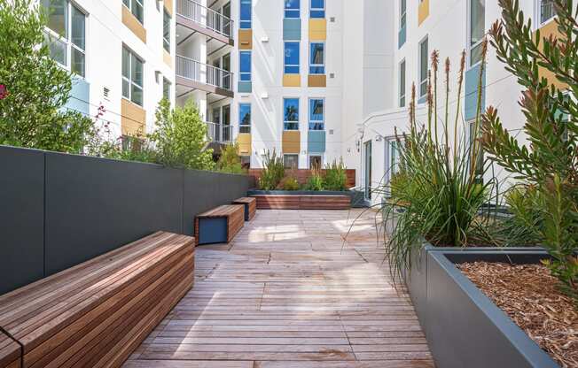 a courtyard with wooden benches and plants in an apartment building