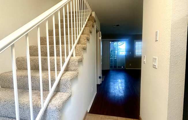 the hallway of a house with stairs and a carpeted floor