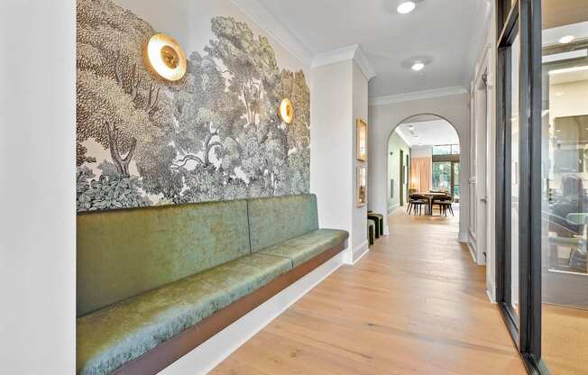 A long hallway with a green bench and a wall with a mural of trees.