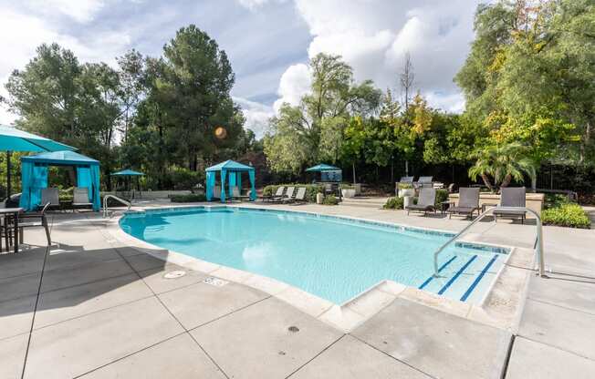 a swimming pool with chairs and umbrellas and trees