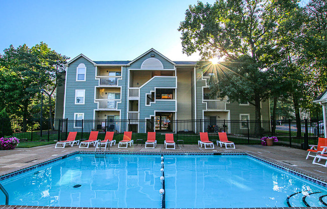 a swimming pool with chairs and a building in the background