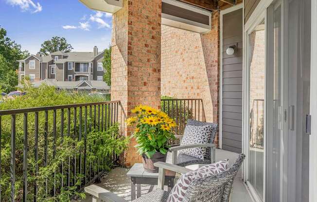A balcony with a table and chairs overlooking a residential area.