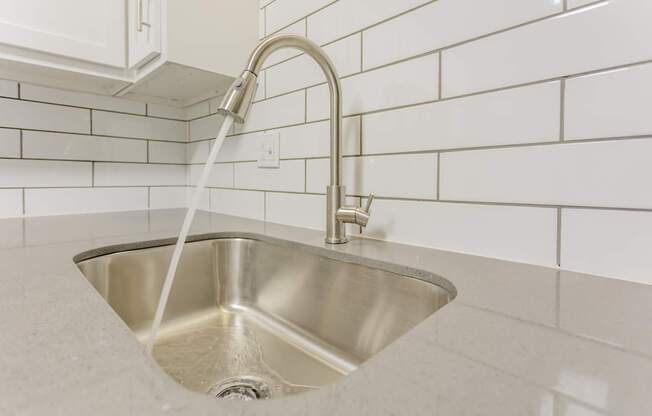 A silver sink with a chrome faucet and a white hose running from the tap.