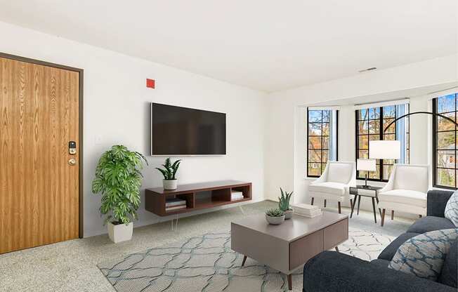 A living room with bay windows, a grey couch, a television, and a rug at Tanglewood Apartments, Oak Creek
