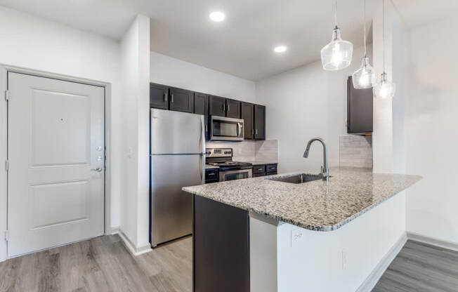 A kitchen with a granite countertop and stainless steel appliances.