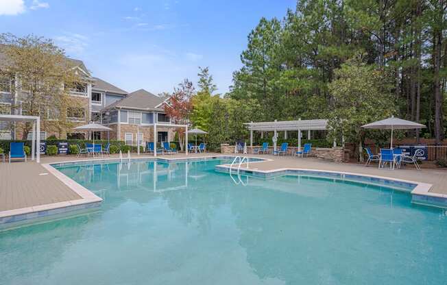 A large swimming pool surrounded by trees and a building.