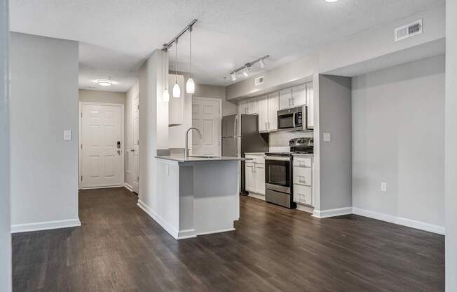A kitchen with white cabinets and a wooden floor.