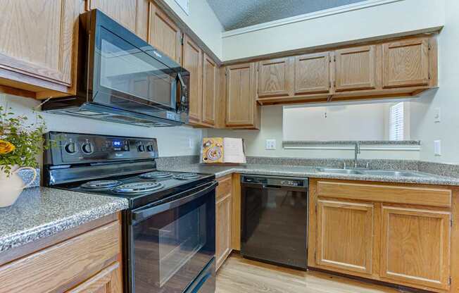 A kitchen with wooden cabinets and black appliances.