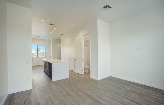 a kitchen and living room with white walls and wood floors