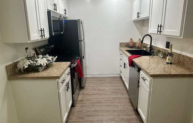 A kitchen with black appliances and white cabinets at Willow Tree Apartments, California, 90505