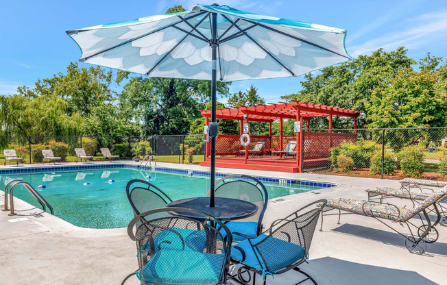 our apartments have a pool and patio with chairs and an umbrella