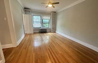 an empty living room with wood floors and a ceiling fan