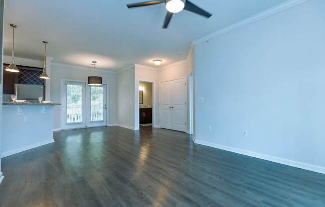 A spacious room with a ceiling fan and wooden flooring.
