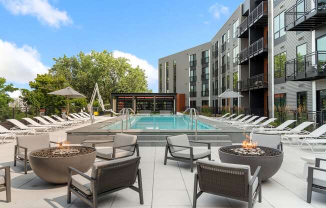 an outdoor pool with lounge chairs and fire pits