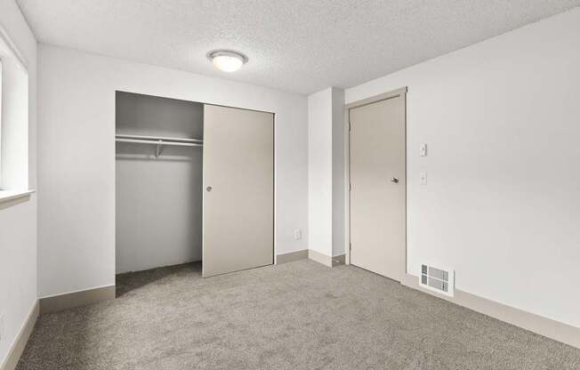 A room with a carpeted floor and two doors.