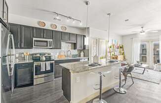 a kitchen with a bar and a living room with a table and chairs