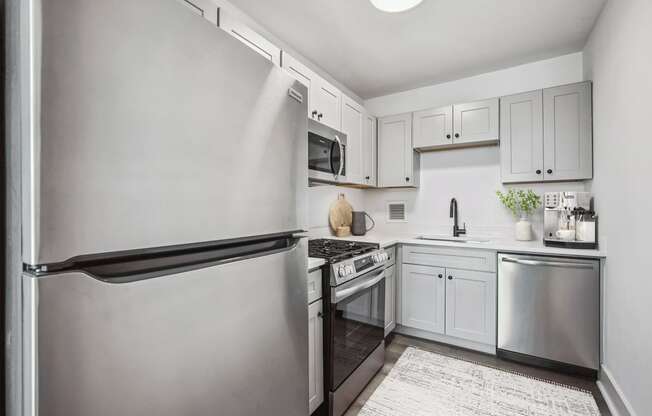 a white kitchen with stainless steel appliances and white cabinets