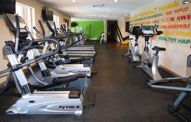 A gym with a row of exercise bikes and a green door in the background.