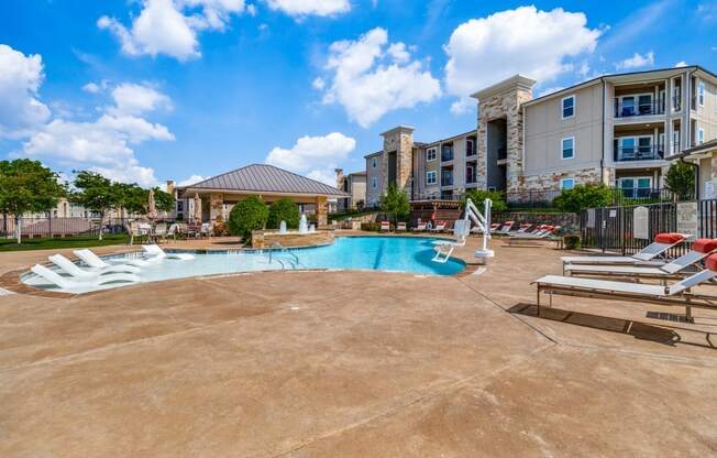 a resort style pool with lounge chairs and a building in the background