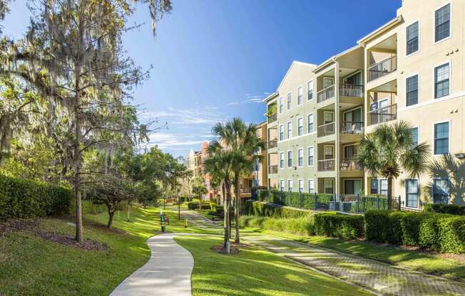 a walkway between apartment buildings with palm trees