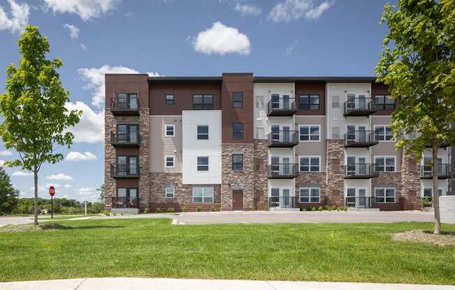 an apartment building with brick and stone exterior and green grass