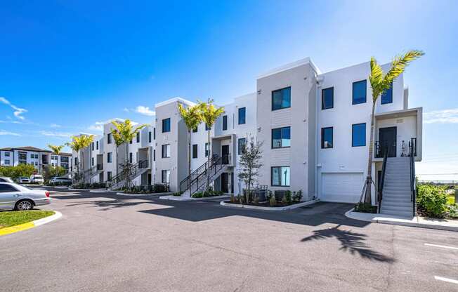 A row of white townhouses with a car parked in front.