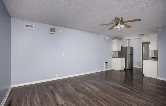 A room with a ceiling fan and a refrigerator.