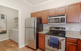 a kitchen with stainless steel appliances and wooden cabinets at Cumberland Place Apartment Homes, Tyler, TX 75703
