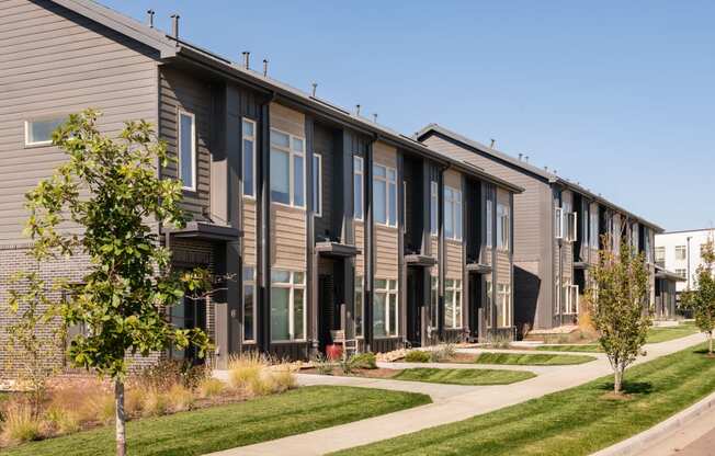 a row of townhomes with a sidewalk and grass