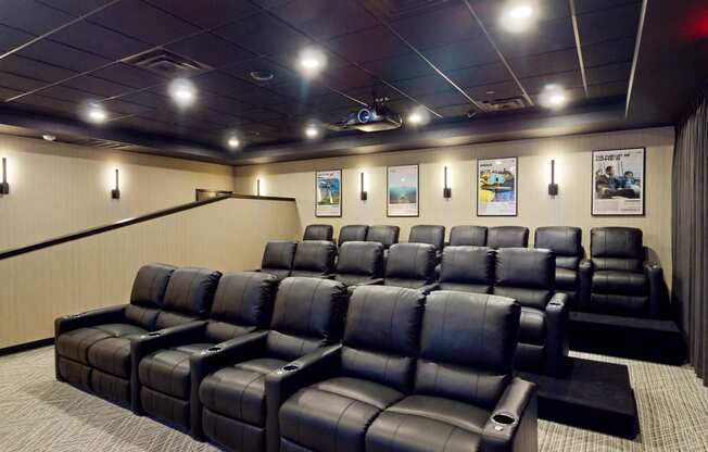 a home theater room with leather seats and a large screen tv