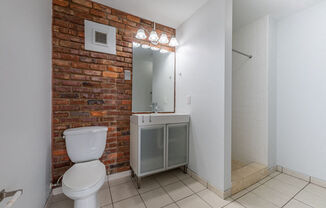 a bathroom with a brick wall and a toilet and a sink