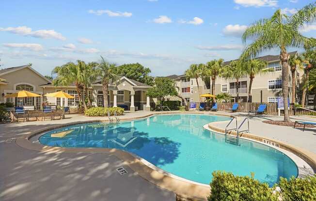 A large swimming pool surrounded by palm trees and lounge chairs.