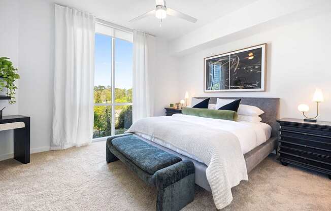A bedroom with a large bed and a view of the outdoors through the window.