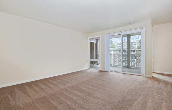 an empty living room with a sliding glass door to a balcony