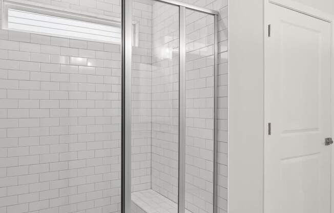 a white tiled bathroom with a shower and a white door