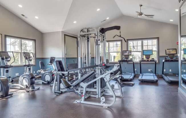 A spacious gym with various exercise equipment and a ceiling fan.