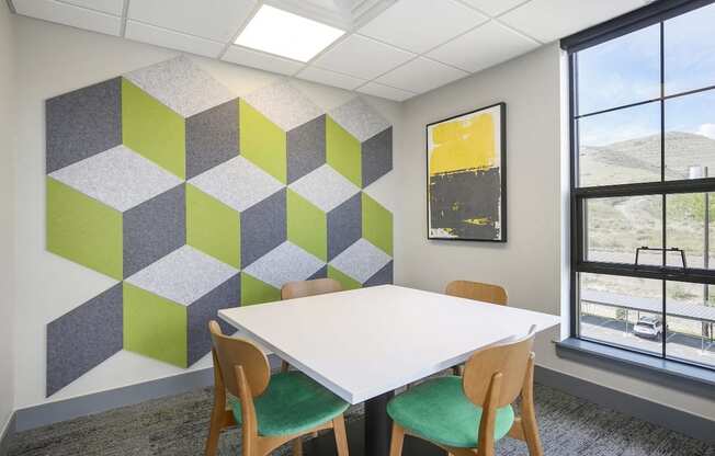 A white table with two chairs in front of a wall with a green and grey geometric pattern.