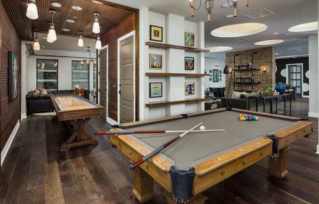 A pool table in a room with a wooden floor and a brick wall.