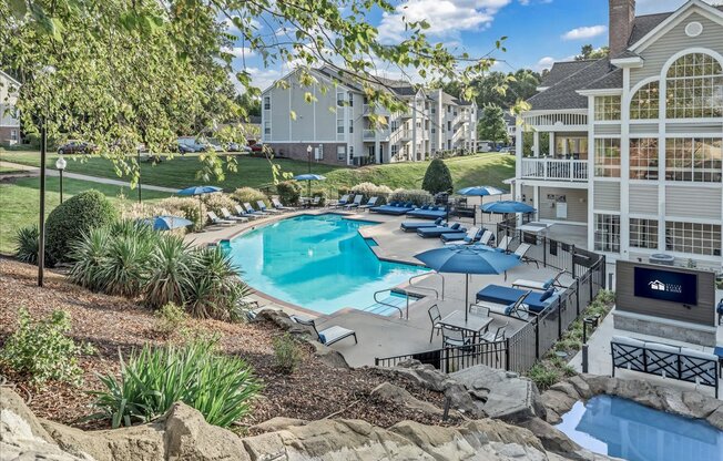 a resort style swimming pool with umbrellas in front of a building