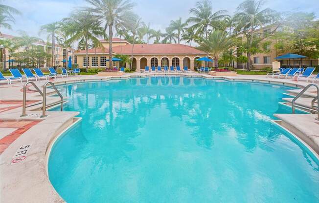 A large swimming pool surrounded by palm trees and lounge chairs.