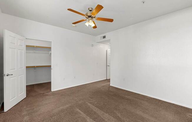 A room with a ceiling fan and carpeted floor.