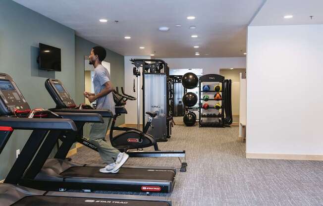 A man is running on a treadmill in a gym.