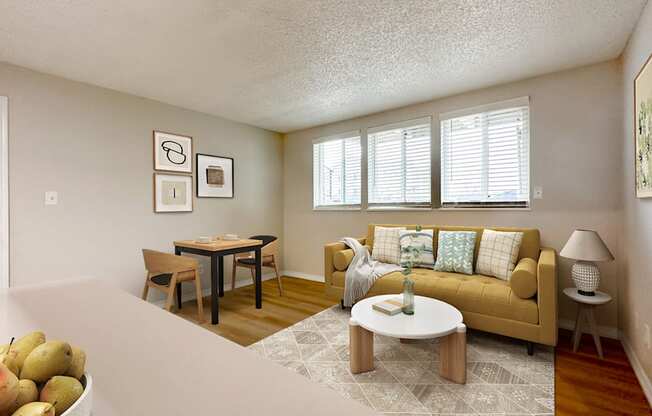 Pet-Friendly Apartments in Aurora, CO– Aurora Meadows – A living room with a yellow couch and a table with a vase on it.